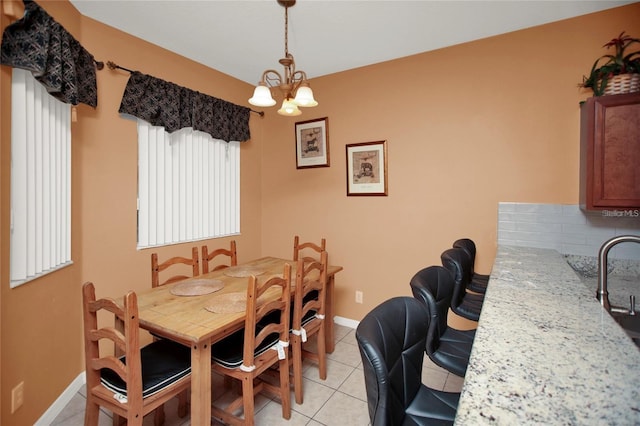 dining space featuring light tile patterned flooring, a notable chandelier, and baseboards