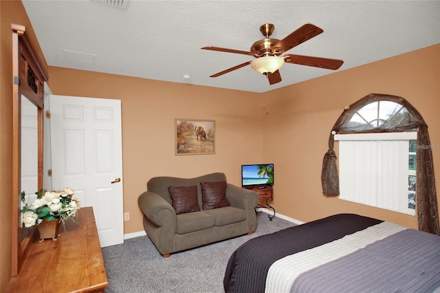 carpeted bedroom with ceiling fan, a textured ceiling, and baseboards