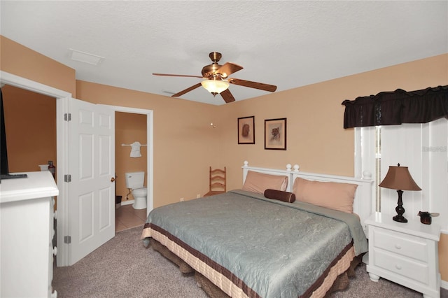 carpeted bedroom with ceiling fan, ensuite bath, and a textured ceiling