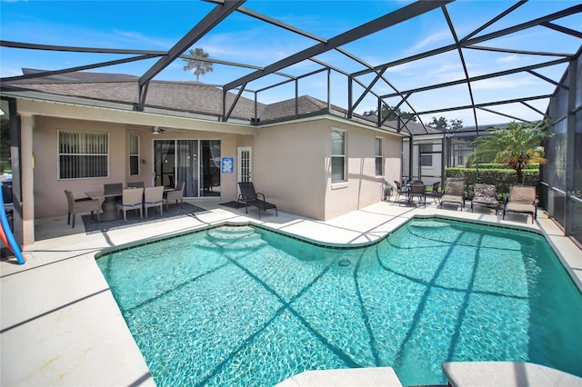 outdoor pool featuring glass enclosure, ceiling fan, and a patio area