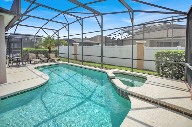 view of pool featuring a patio area, glass enclosure, and a pool with connected hot tub