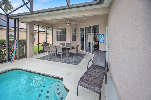 pool with glass enclosure, outdoor dining area, a patio, and ceiling fan