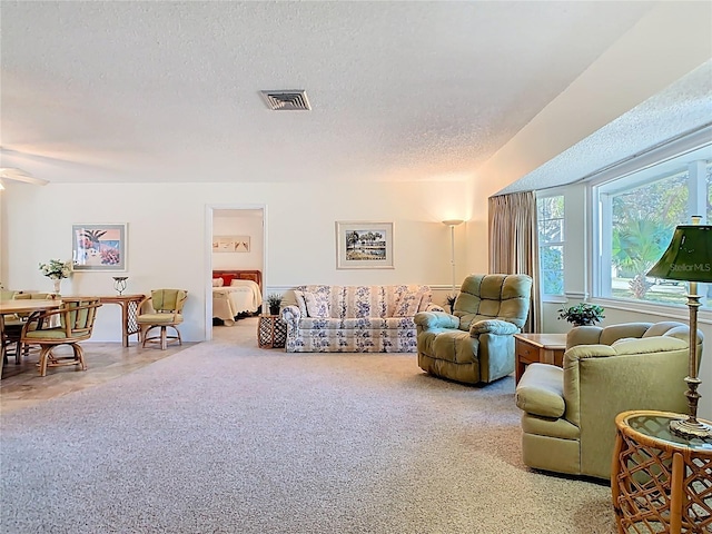 living room featuring visible vents, a textured ceiling, and carpet flooring