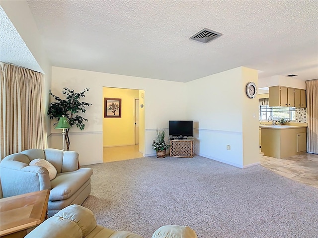 living area featuring visible vents, light colored carpet, and a textured ceiling