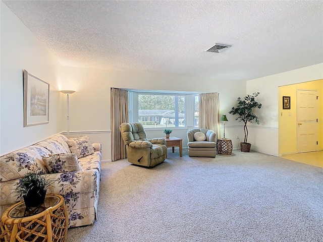 living room featuring carpet, visible vents, and a textured ceiling