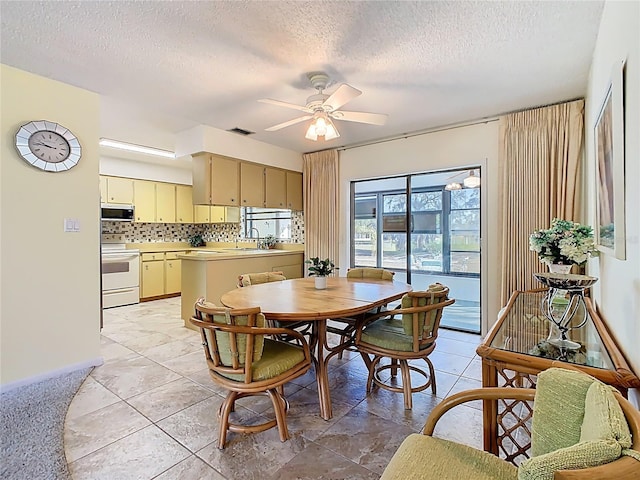 dining area featuring light tile patterned floors, visible vents, a textured ceiling, and a ceiling fan