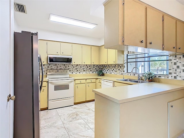 kitchen with visible vents, appliances with stainless steel finishes, cream cabinets, a peninsula, and a sink