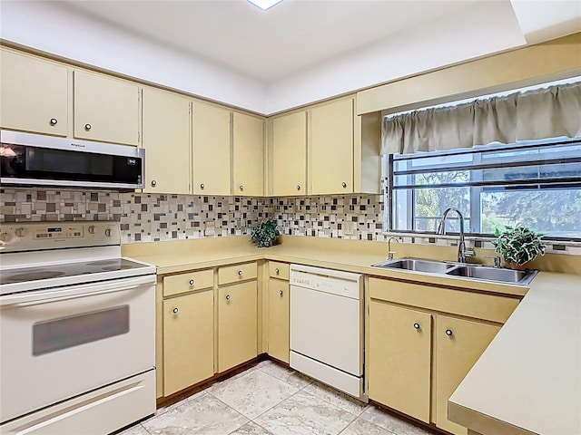 kitchen with white appliances, a sink, light countertops, cream cabinets, and tasteful backsplash