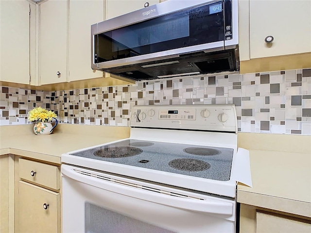 kitchen with decorative backsplash, stainless steel microwave, electric range, and light countertops