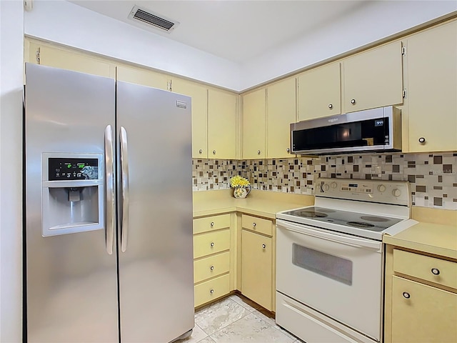 kitchen with visible vents, tasteful backsplash, cream cabinets, appliances with stainless steel finishes, and light countertops