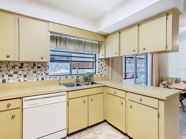 kitchen featuring cream cabinetry, dishwasher, a peninsula, and a sink