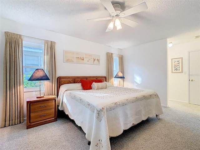 bedroom with multiple windows, a textured ceiling, and light carpet