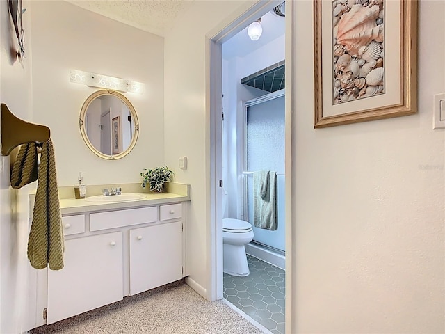 bathroom featuring toilet, a textured ceiling, a shower stall, baseboards, and vanity