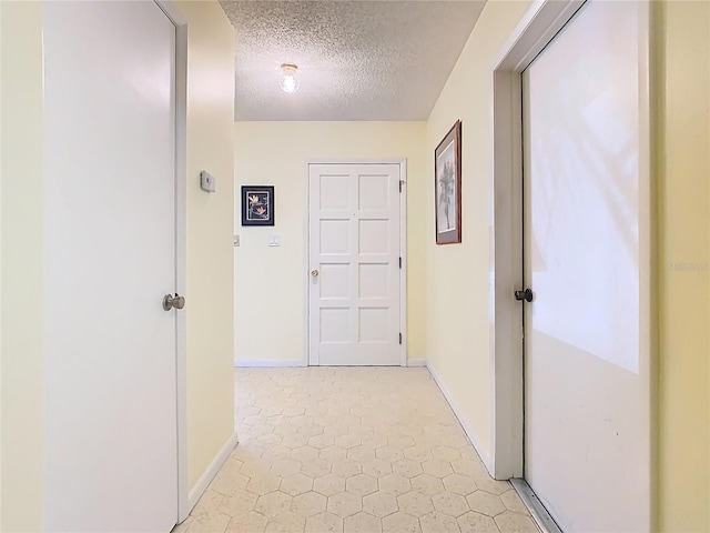 hallway featuring baseboards and a textured ceiling