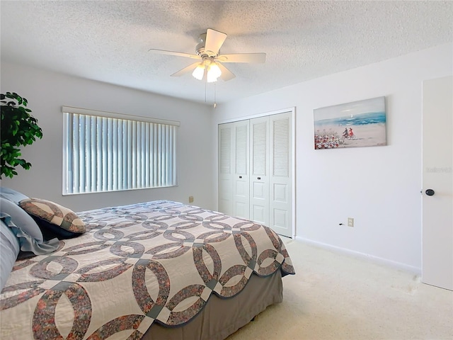 bedroom featuring a ceiling fan, baseboards, a closet, a textured ceiling, and light carpet