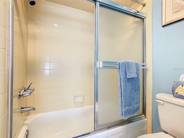 full bath featuring toilet and shower / bath combination with glass door