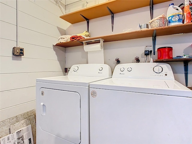 laundry room with laundry area, separate washer and dryer, and wood walls