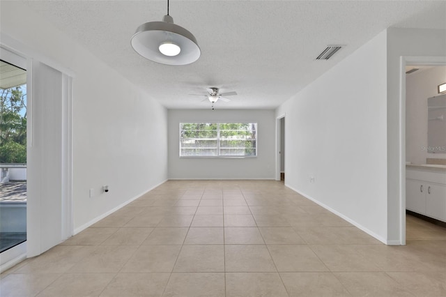 spare room with light tile patterned floors, a ceiling fan, baseboards, visible vents, and a textured ceiling