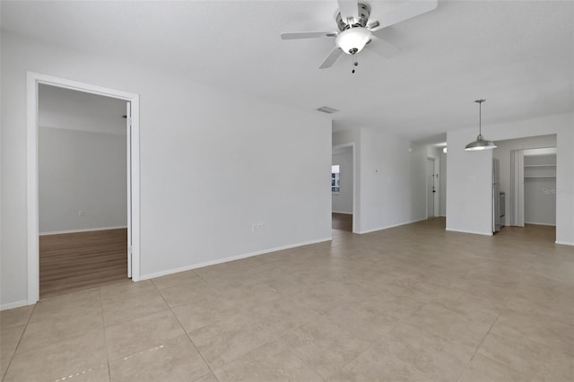 unfurnished living room featuring visible vents, baseboards, and ceiling fan