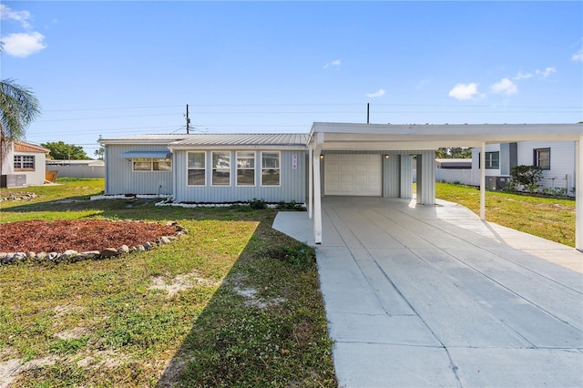 view of front facade featuring an attached carport, a front lawn, concrete driveway, and a garage