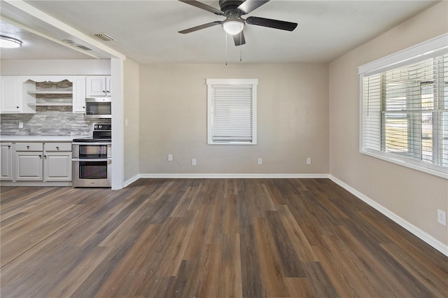 unfurnished living room with visible vents, baseboards, dark wood-type flooring, and ceiling fan