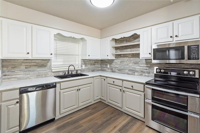 kitchen with a sink, open shelves, stainless steel appliances, light countertops, and dark wood-style flooring