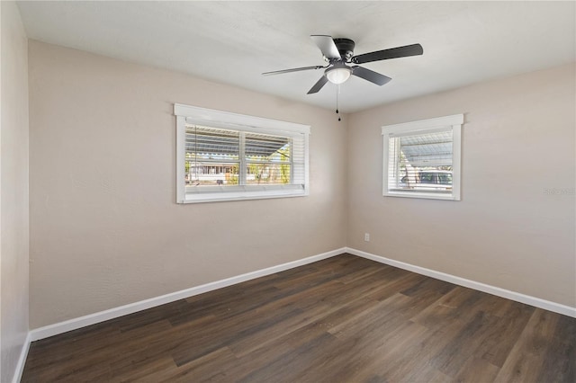 spare room with dark wood finished floors, baseboards, and ceiling fan