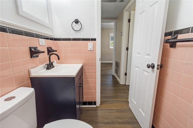 bathroom with vanity, tile walls, toilet, and wood finished floors