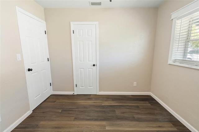 unfurnished room with visible vents, baseboards, and dark wood-style flooring