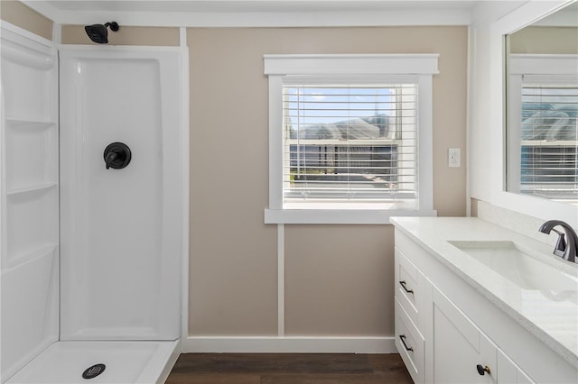 full bath with vanity, wood finished floors, baseboards, and a stall shower