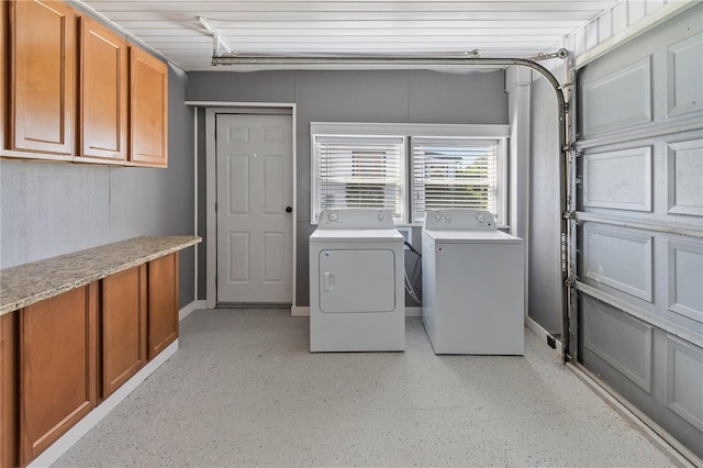 washroom with cabinet space, washer and dryer, and baseboards