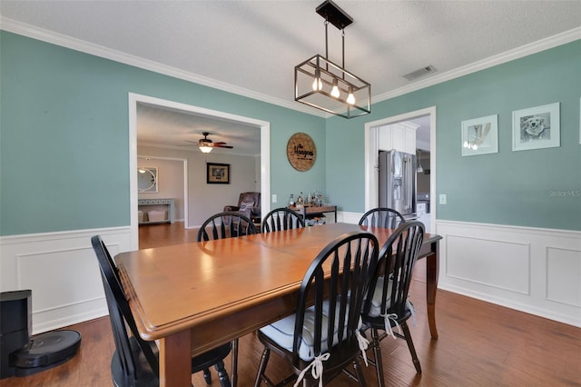 dining room featuring dark wood-style floors, visible vents, and wainscoting