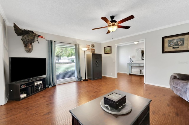 living room with a textured ceiling, wood finished floors, a ceiling fan, and crown molding