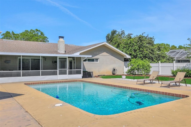 view of pool with a patio area, a fenced in pool, fence, and a sunroom