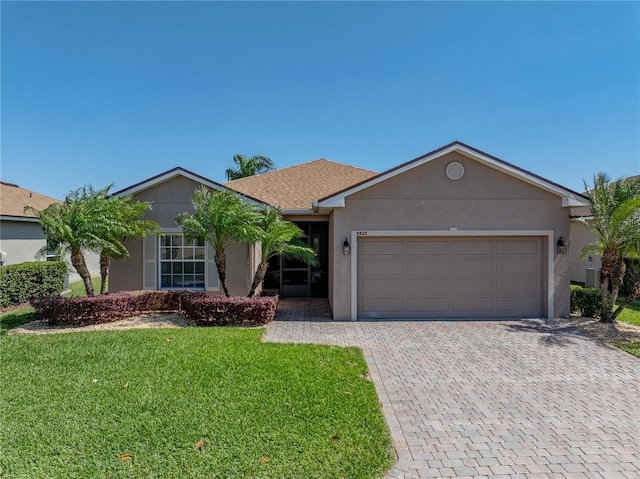 ranch-style house featuring a front lawn, decorative driveway, stucco siding, and an attached garage