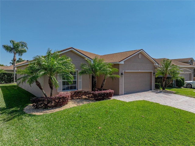ranch-style home featuring a front lawn, decorative driveway, stucco siding, and a garage