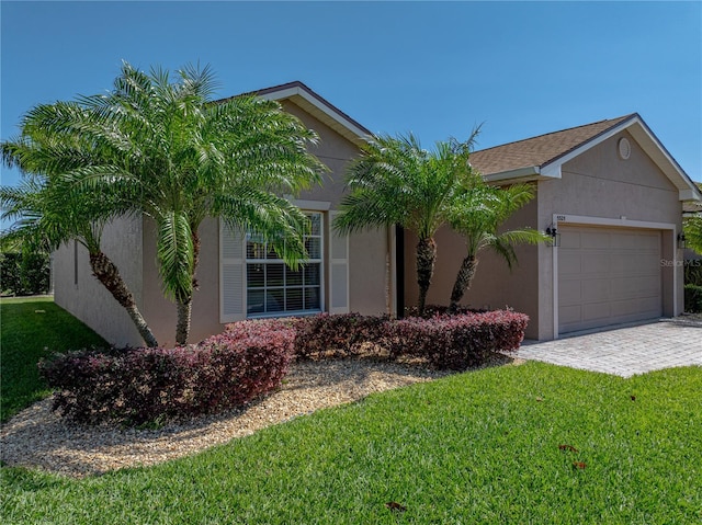 view of front of house featuring a garage, stucco siding, and a front lawn