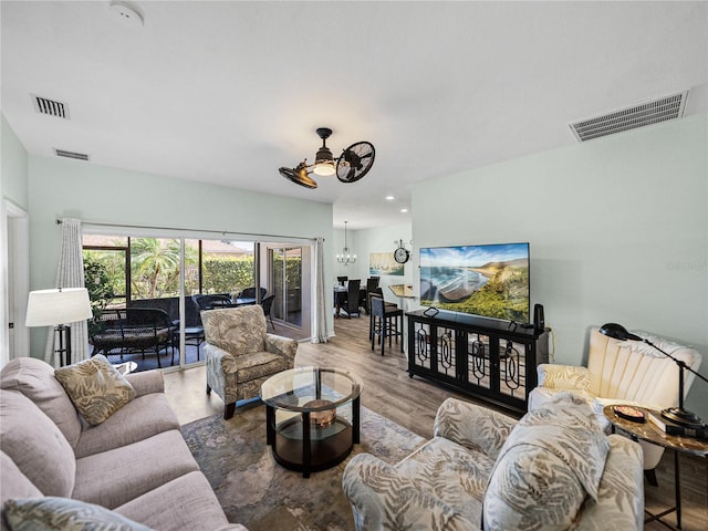 living room with wood finished floors, ceiling fan with notable chandelier, and visible vents