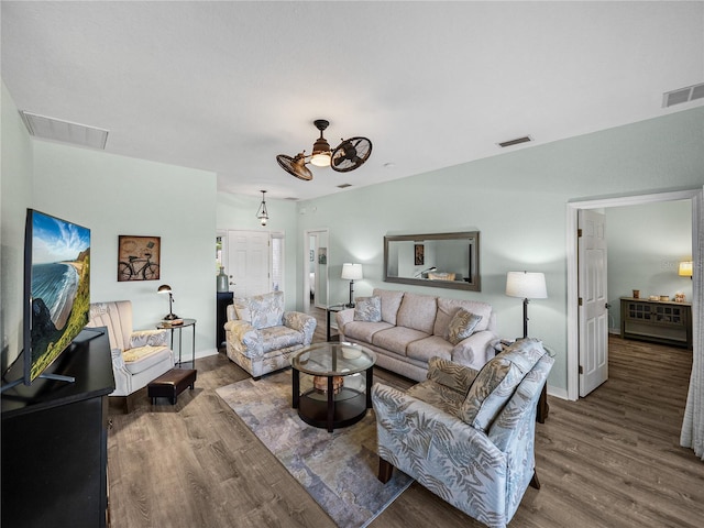 living room with visible vents, wood finished floors, and ceiling fan