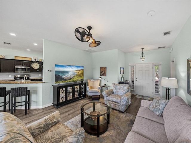 living room featuring baseboards, visible vents, wood finished floors, and recessed lighting