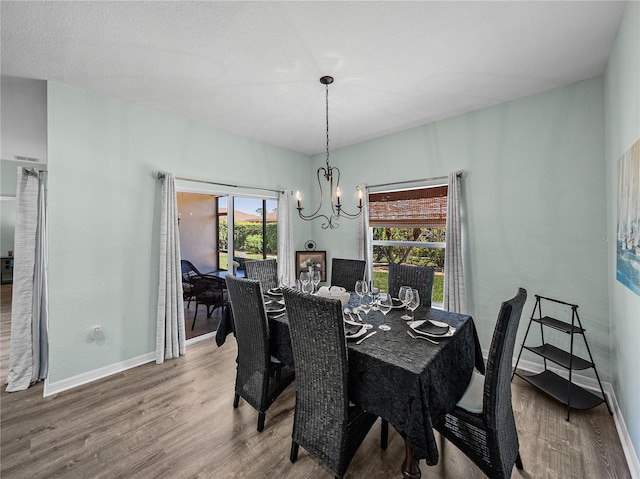 dining area featuring baseboards, wood finished floors, and an inviting chandelier