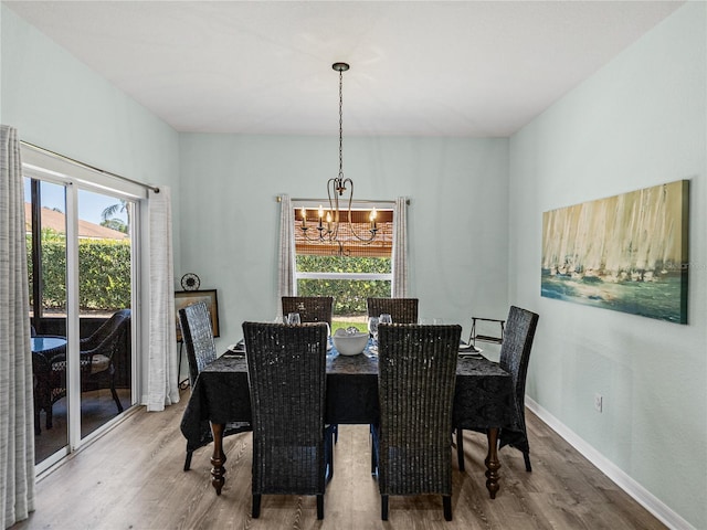 dining space featuring a healthy amount of sunlight, wood finished floors, baseboards, and a chandelier
