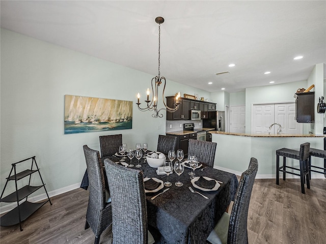 dining area with baseboards, recessed lighting, dark wood-type flooring, and an inviting chandelier