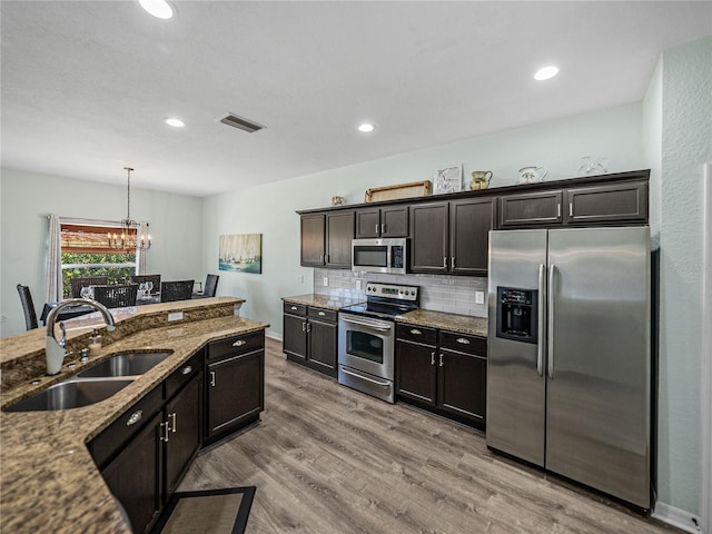 kitchen featuring decorative backsplash, visible vents, wood finished floors, appliances with stainless steel finishes, and a sink