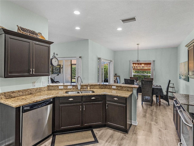 kitchen with a sink, light stone countertops, appliances with stainless steel finishes, visible vents, and light wood-style floors
