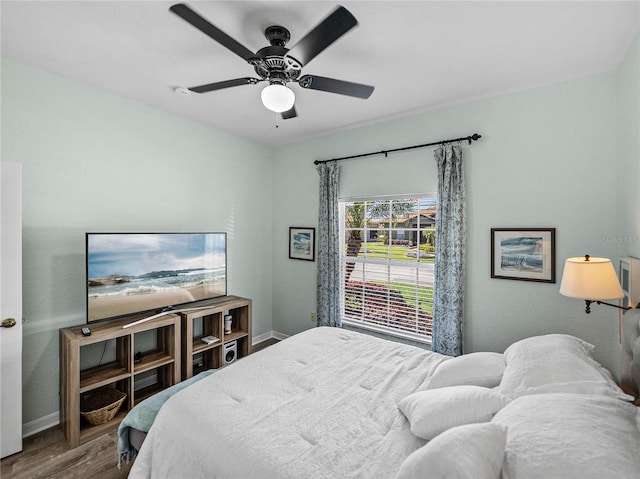 bedroom featuring baseboards, wood finished floors, and ceiling fan