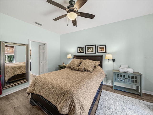 bedroom with a ceiling fan, wood finished floors, baseboards, and visible vents