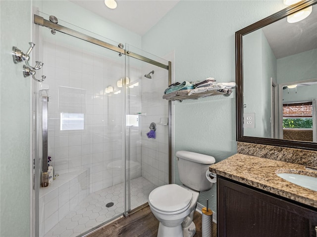 bathroom with vanity, toilet, a shower stall, and wood finished floors