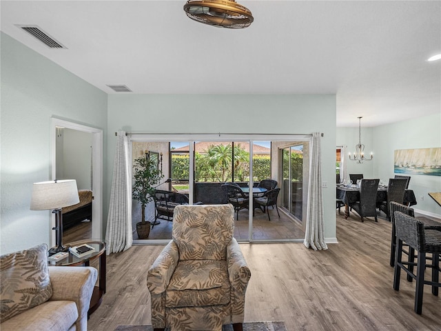living room with wood finished floors, baseboards, a chandelier, and visible vents