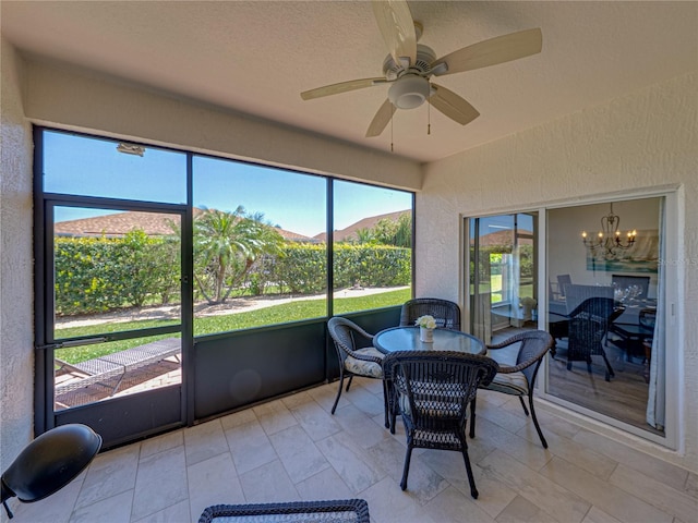 sunroom / solarium with ceiling fan with notable chandelier and outdoor dining area